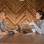 Een vrouw interviewt een man en houden een gesprek op een tafel met een laptop.