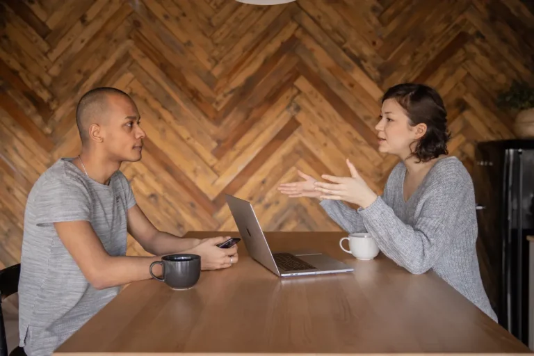 Een vrouw interviewt een man en houden een gesprek op een tafel met een laptop.