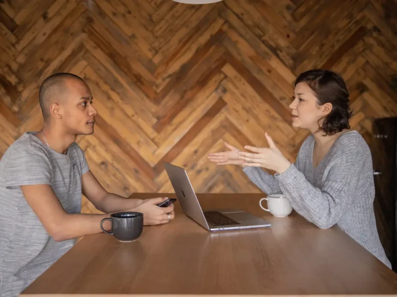 Een vrouw interviewt een man en houden een gesprek op een tafel met een laptop.