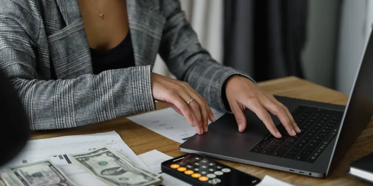 Vrouw berekent met een calculator en laptop.