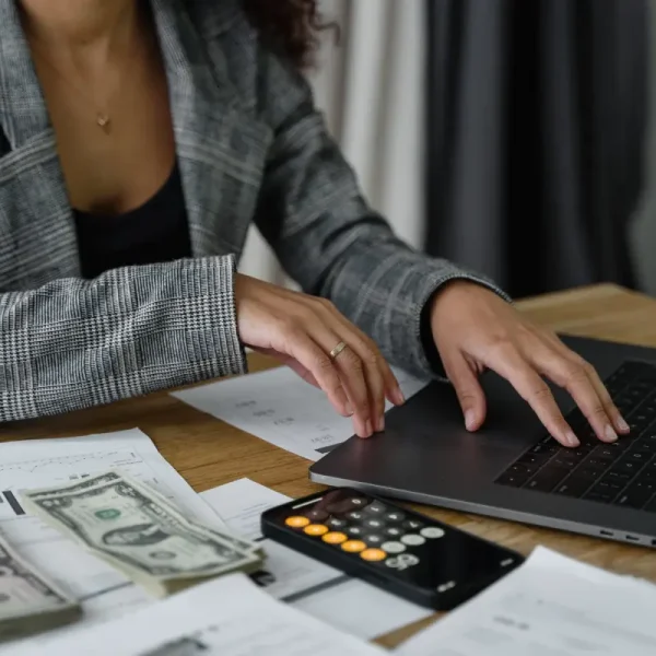 Vrouw berekent met een calculator en laptop.