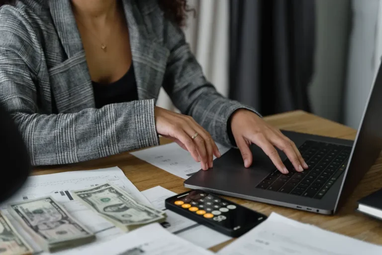 Vrouw berekent met een calculator en laptop.