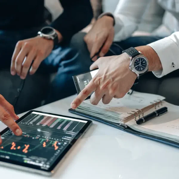 Twee personen houden zich bezig met een tablet die op tafel ligt.