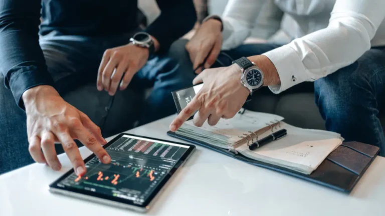 Twee personen houden zich bezig met een tablet die op tafel ligt.