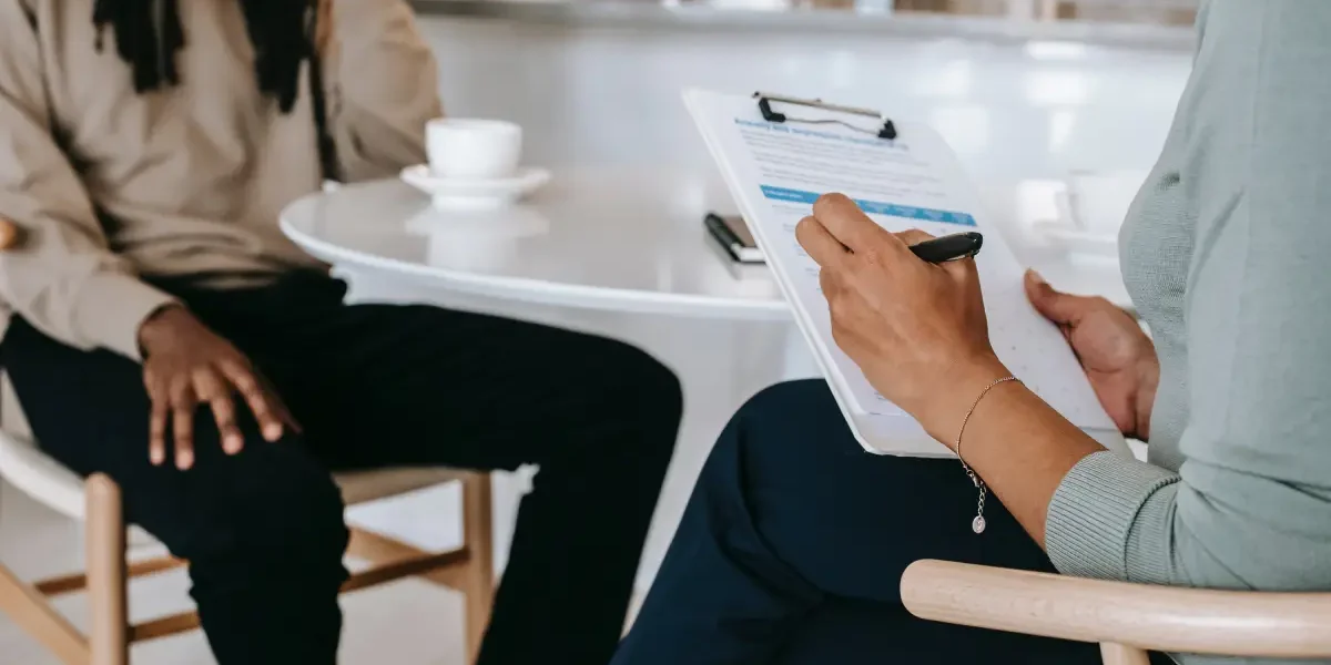 Twee personen waaronder een werkzoekende en een recruiter zitten beiden op een stoel en houden een interview voor een baan.