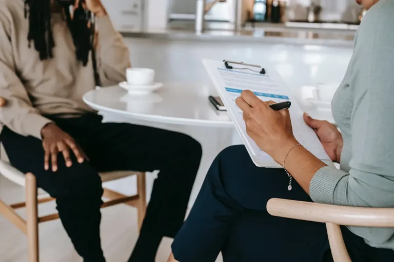 Twee personen waaronder een werkzoekende en een recruiter zitten beiden op een stoel en houden een interview voor een baan.