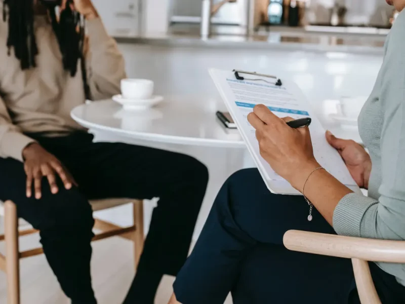 Twee personen waaronder een werkzoekende en een recruiter zitten beiden op een stoel en houden een interview voor een baan.