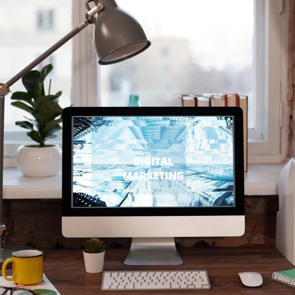 Een laptop met de woorden digitale marketing erop, zittend op een bureau.
