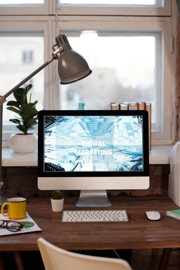 Een laptop met de woorden digitale marketing erop, zittend op een bureau.