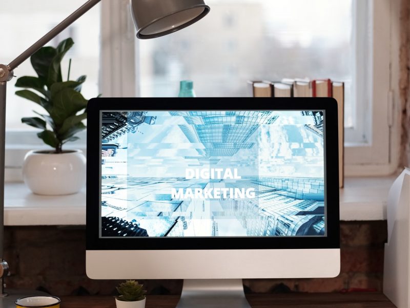 Een laptop met de woorden digitale marketing erop, zittend op een bureau.