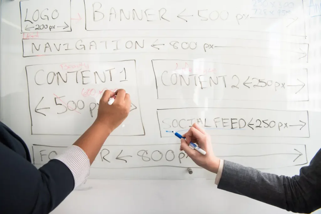 Twee professionals schrijven op een whiteboard met aantekeningen over contentstrategie.