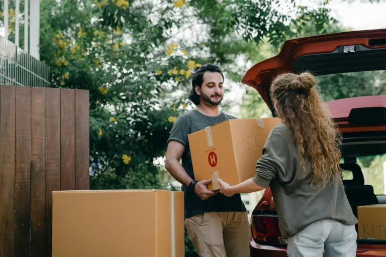 stel met 2 grote verhuisdozen voor de auto.