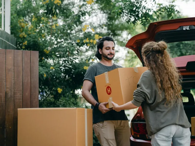 stel met 2 grote verhuisdozen voor de auto.